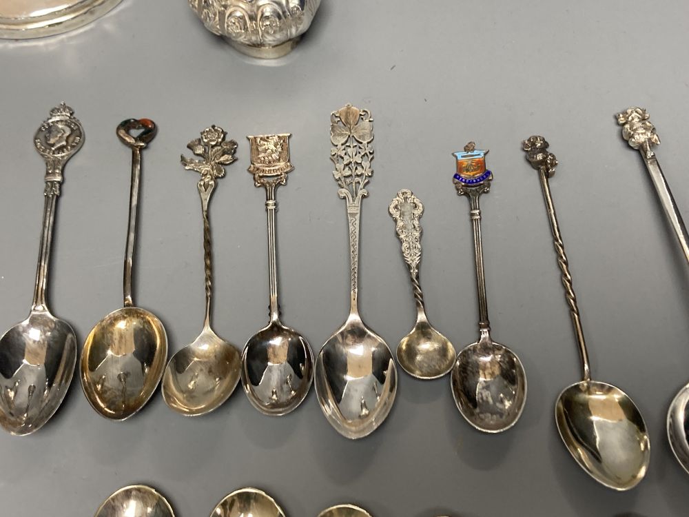A silver dwarf candlestick, two silver condiments and a group of assorted silver, white metal and plated mainly commemorative spoons,